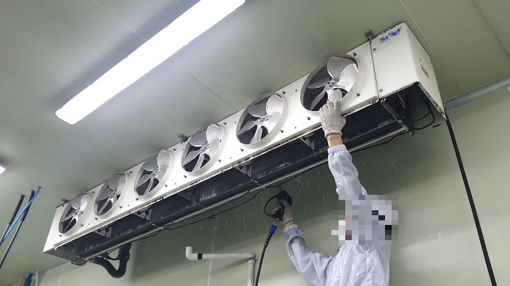 식품공장 HACCP청소 작업 진행 중 작업자가 유니트쿨러 냉각 핀 틈새의 오염물질을 고압 세척 작업을 진행하고 있습니다.